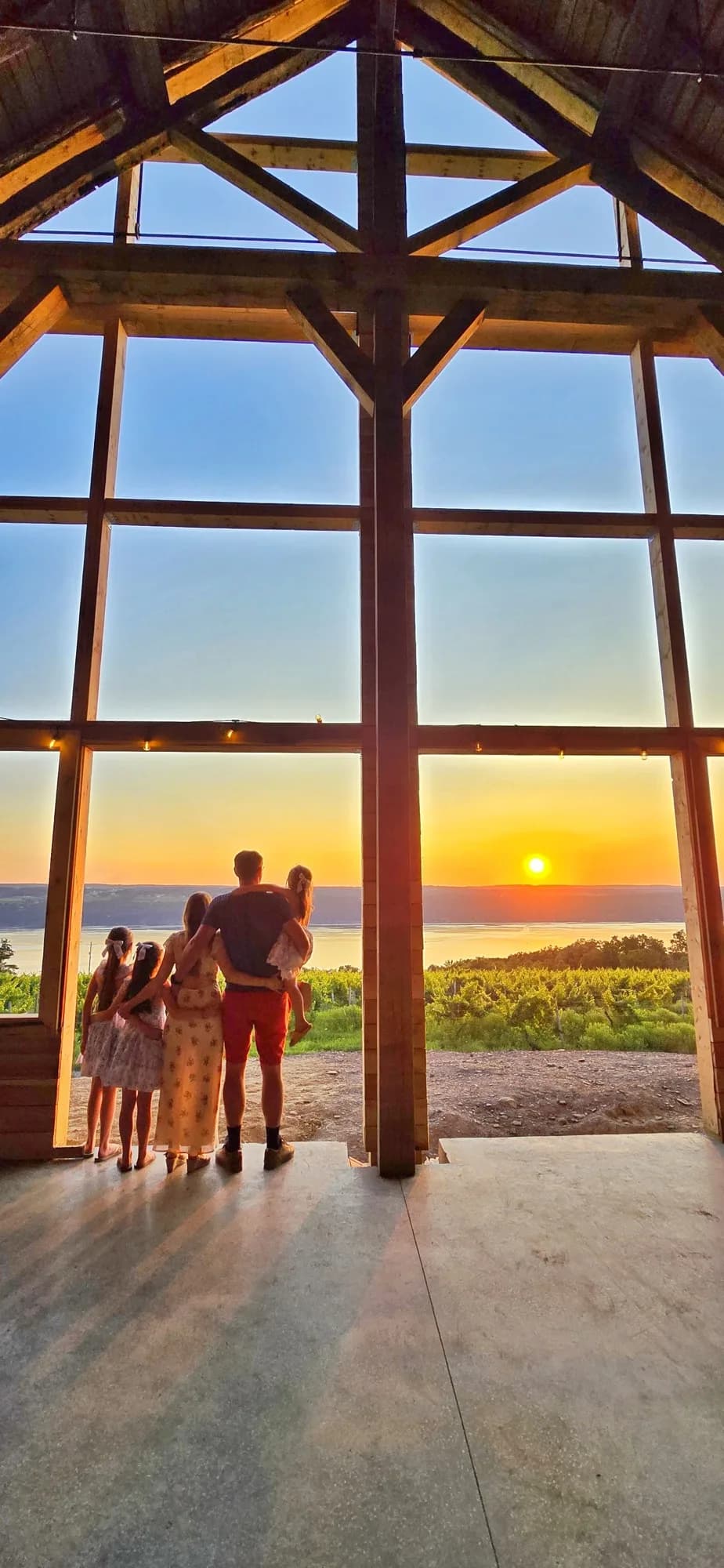 The LeSeurre family looking out over Seneca Lake through the open frame of the 1487 barn at sunset